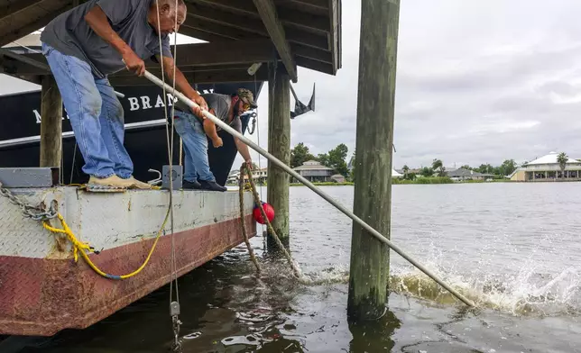 Norman Bouisse, 76, left, and Jeremy Adam, back left, one of the captains for the 100-foot trawler Master Brandon, work at tying extra lines around a piling in their attempt to batten down their boat in anticipation of Hurricane Francine along the Louisiana coast in Lafitte on Monday, Sept. 9, 2024. (Chris Granger/The Times-Picayune/The New Orleans Advocate via AP)