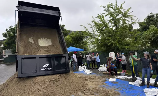 Residents fill up sand bags to protect their homes in anticipation of Tropical Storm Francine, Tuesday, Sept. 10, 2024, at a distribution site in a parking lot in New Orleans. (AP Photo/Jack Brook)