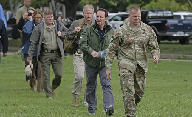 Louisiana National Guard Maj. Gen. Thomas C. Friloux, right, leads Louisiana Gov. Jeff Landry and Louisiana State Police Col Robert P. Hodges to a helicopter for an aerial tour of damage from Hurricane Francine, Thursday, Sept. 12, 2024, in Baton Rouge, La., (Hilary Scheinuk/The Advocate via AP)