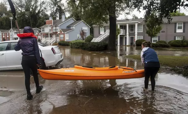 Two women maneuver a kayak into position to retrieve belongings at a flooded apartment complex after Hurricane Helene passed the area on Friday, Sept. 27, 2024, in Atlanta. (AP Photo/Ron Harris)