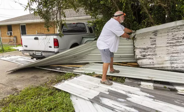 Rick Armstrong removes metal roofing that flew from a restaurant about a block from his house and onto his truck in his driveway during Hurricane Francine on Thursday, Sept. 12, 2024 in Houma, La. (Chris Granger /The Times-Picayune/The New Orleans Advocate via AP)