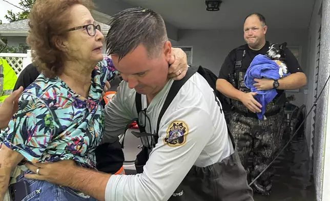 This photo provided by Venice Police Department rescue crews assist residents after conducting door-to-door wellness checks, in coastal areas that were flooded by Hurricane Helene on Friday, Sept. 27, 2024 in Venice, Fla . (Venice Police Department via AP)