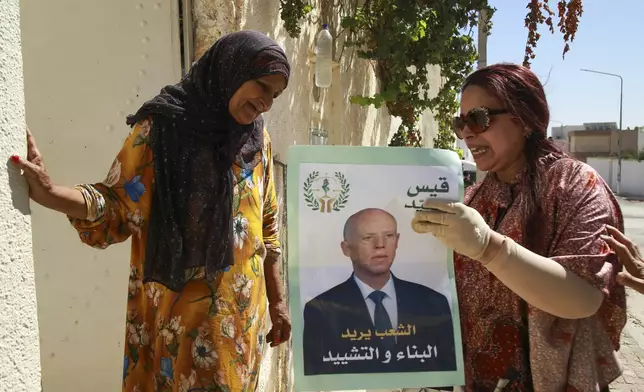 A supporter of Tunisian President and candidate for re-election Kais Saied meets with residents of a neighbourhood during a campaign tour, in Ariana, Tunisia, Thursday, Sept. 26, 2024. (AP Photo/Anis Mili)