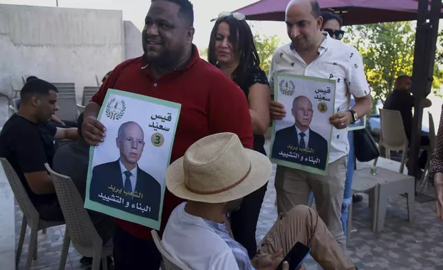 Supporters of Tunisian President and candidate for re-election Kais Saied meet with residents of a neighbourhood during a campaign tour, in Ariana, Tunisia, Thursday, Sept. 26, 2024. (AP Photo/Anis Mili)