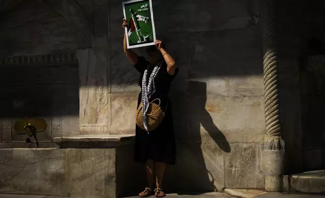 A woman holds up a poster that reads: "The Land" during a protest in memory of Aysenur Ezgi Eygi, a 26 year-old Turkish-American activist killed by the Israeli military, in Istanbul, Turkey, Saturday, Sept. 14, 2024. (AP Photo/Francisco Seco)