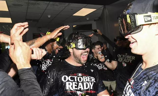 The Cleveland Guardians, including Austin Hedges, center, celebrate after their 10-inning win over the Minnesota Twins in a baseball game to clinch a playoff berth Thursday, Sept. 19, 2024, in Cleveland. (AP Photo/Nick Cammett)