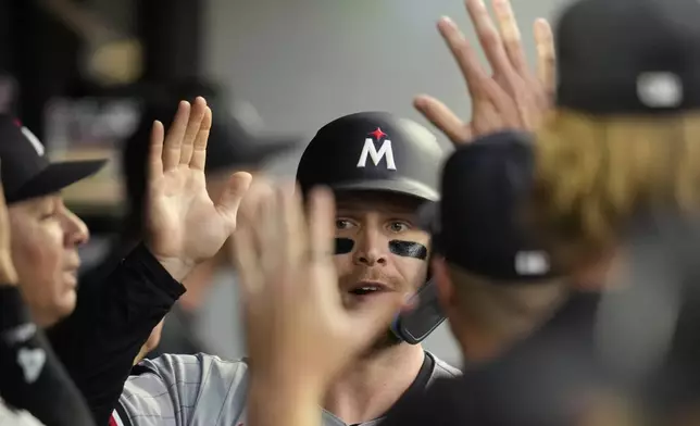 Minnesota Twins' Ryan Jeffers, center, gets high-fives in the dugout after scoring in the third inning of a baseball game against the Cleveland Guardians, Monday, Sept. 16, 2024, in Cleveland. (AP Photo/Sue Ogrocki)