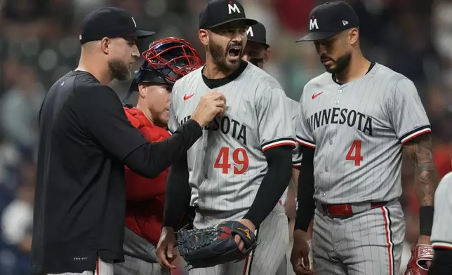 Minnesota Twins starting pitcher Pablo Lopez (49) reacts as he is taken out of the game by manager Rocco Baldelli, left, in the seventh inning of a baseball game, Monday, Sept. 16, 2024, in Cleveland. Twins's Carlos Correa is at right. (AP Photo/Sue Ogrocki)