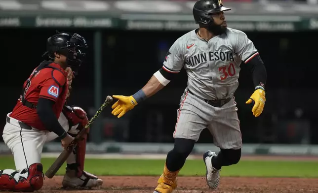 Minnesota Twins' Carlos Santana (30) watches his single with Cleveland Guardians catcher Bo Naylor, left, in the sixth inning of a baseball game Monday, Sept. 16, 2024, in Cleveland. (AP Photo/Sue Ogrocki)