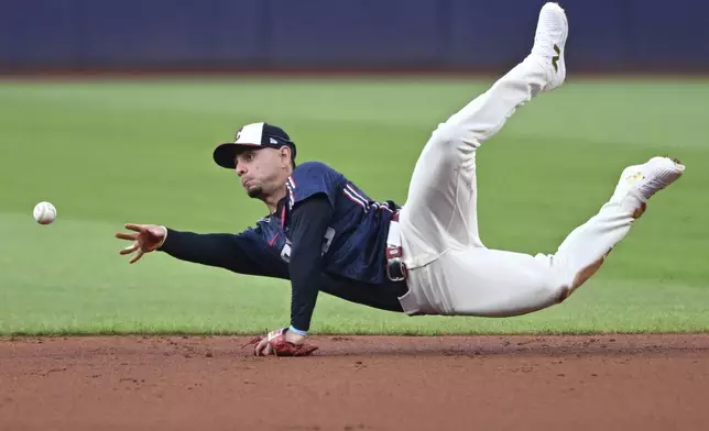 Cleveland Guardians second baseman Andres Gimenez flips the ball to shortstop Brayan Rocchio to get out Minnesota Twins' Carlos Correa during the first inning of a baseball game, Wednesday, Sept. 18, 2024, in Cleveland. (AP Photo/David Dermer)