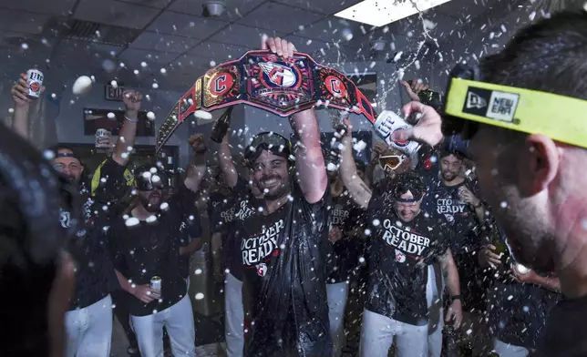 The Cleveland Guardians celebrate in the clubhouse after they defeated the Minnesota Twins to clinch a baseball playoff berth, Thursday, Sept. 19, 2024, in Cleveland. (AP Photo/Nick Cammett)