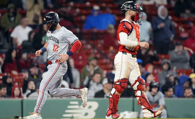 Minnesota Twins' Kyle Farmer (12) scores behind Boston Red Sox catcher Connor Wong, right, on a single by Trevor Larnach during the 12th inning of a baseball game, Friday, Sept. 20, 2024, in Boston. (AP Photo/Michael Dwyer)