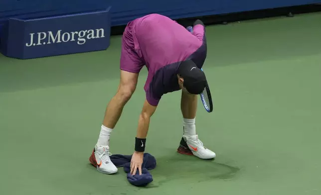 Jack Draper, of Great Britain, wipes the court against Jannik Sinner, of Italy, during the men's singles semifinals of the U.S. Open tennis championships, Friday, Sept. 6, 2024, in New York. (AP Photo/Seth Wenig)