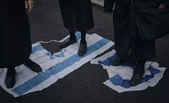 Haredi Jews step on the Israeli flag to protest against Prime Minister of Israel Benjamin Netanyahu in front of his hotel during the 79th session of the United Nations General Assembly, in New York, on Friday, Sept. 27, 2024. (AP Photo/Andres Kudacki)