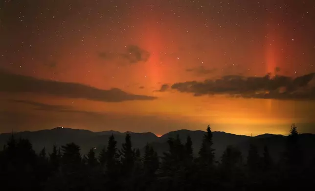 Flares of northern lights color the sky over the White Mountains just after midnight, Friday, Sept. 13, 2024, as viewed from a mountaintop in Chatham, N.H. Lights on the summit of Mount Washington can be seen on the ridgeline at left. (AP Photo/Robert F. Bukaty)