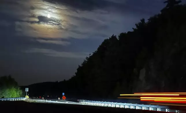 In this long exposure photo, a ring forms around the moon as cars drive along Mt. Major Highway near Lake Winnipesaukee in Alton Bay, N.H., Thursday, Sept. 12, 2024, as Canada and northern U.S. cities experience moderate solar storms. (AP Photo/Caleb Jones)