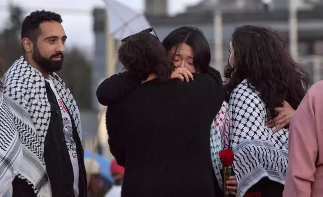 Sue Han, facing, is hugged after speaking of her friend, the 26-year old Aysenur Ezgi Eygi, killed recently in the occupied West Bank, during vigil on Alki Beach, Wednesday, Sept. 11, 2024, in Seattle. Eygi grew up in Seattle, attended Seattle Public Schools and graduated from the University of Washington. Left is another friend Yoseph Ghazal, who also spoke. (AP Photo/John Froschauer)