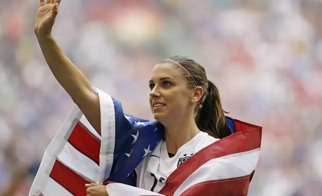 FILE - United States' Alex Morgan is draped in the U.S. flag as she waves to fans after the U.S. beat Japan 5-2 in the FIFA Women's World Cup soccer championship in Vancouver, British Columbia, Canada, Sunday, July 5, 2015. (AP Photo/Elaine Thompson, File)