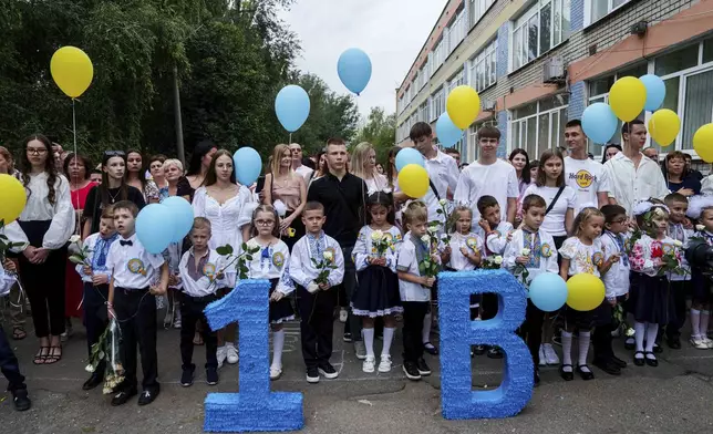 First-grades wait for the beginning of the traditional ceremony for the first day of school in Zaporizhzhia, Ukraine, Sunday Sept. 1, 2024. Zaporizhzhia schoolchildren celebrated the traditional first day of school near the frontline. With the front just 40 kilometers away, the war is never far from the minds of teachers and families. (AP Photo/Evgeniy Maloletka)