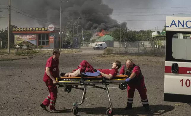 Paramedics take an injured colleague to the ambulance after twin Russian bombings in Kharkiv, Ukraine, Sunday Sept. 1, 2024. (AP Photo/George Ivanchenko)