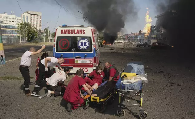 Paramedics give first aid to injured colleagues near an ambulance after twin Russian bombings in Kharkiv, Ukraine, Sunday Sept. 1, 2024. (AP Photo/George Ivanchenko)