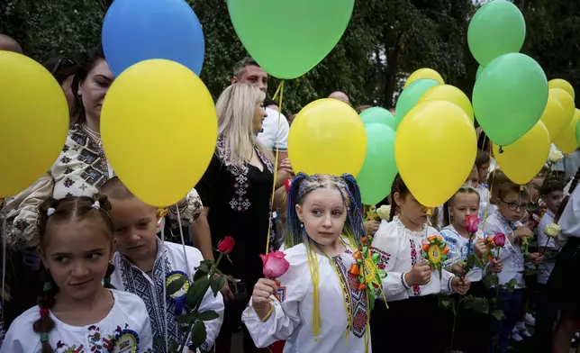 First-grades hold balloons during the traditional ceremony for the first day of school in Zaporizhzhia, Ukraine, Sunday Sept. 1, 2024. Zaporizhzhia schoolchildren celebrated the traditional first day of school near the frontline. With the front just 40 kilometers away, the war is never far from the minds of teachers and families. (AP Photo/Evgeniy Maloletka)