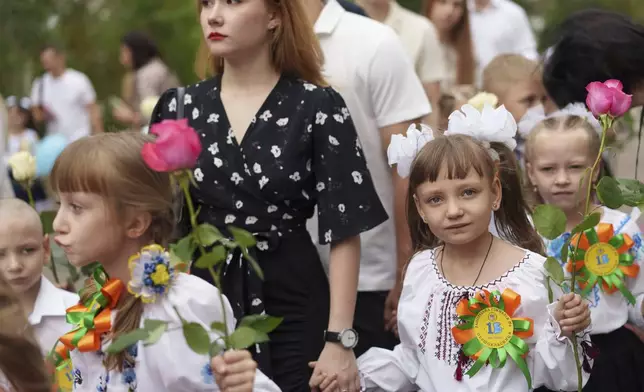 First-grades walk to the traditional ceremony for the first day of school in Zaporizhzhia, Ukraine, Sunday Sept. 1, 2024. Zaporizhzhia schoolchildren celebrated the traditional first day of school near the frontline. With the front just 40 kilometers away, the war is never far from the minds of teachers and families. (AP Photo/Evgeniy Maloletka)