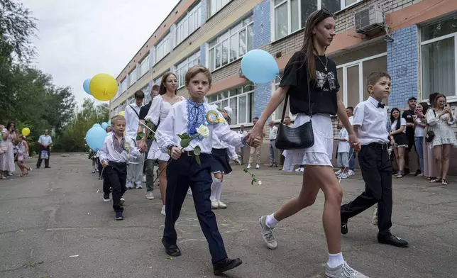 First-grades walk to the traditional ceremony for the first day of school in Zaporizhzhia, Ukraine, Sunday Sept. 1, 2024. Zaporizhzhia schoolchildren celebrated the traditional first day of school near the frontline. With the front just 40 kilometers away, the war is never far from the minds of teachers and families. (AP Photo/Evgeniy Maloletka)