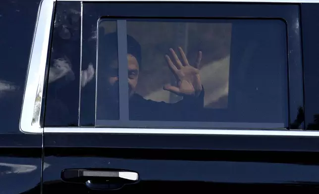 Ukrainian President Volodymyr Zelenskyy waves from the back seat of a U.S. Secret Service vehicle as his motorcade departs the Wilkes-Barre/Scranton International Airport in Pittston Township, Pa., en route to the Scranton Army Ammunition Plant in Scranton, Pa., on Sunday, Sept. 22, 2024. (Christopher Dolan/The Times-Tribune via AP)