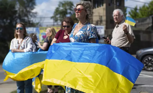 Kristina Ramanauskas, a first generation Lithuanian, waves a Ukrainian flag before President of Ukraine Volodymyr Zelenskyy's motorcade arrives at the Scranton Army Ammunition Plant in Scranton on Sunday, Sept. 22, 2024. (AP Photo/Laurence Kesterson)