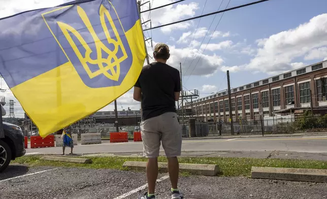 Maxim Trushin, a native of Ukraine, waves a flag before President of Ukraine Volodymyr Zelenskyy's motorcade arrives at the Scranton Army Ammunition Plant in Scranton on Sunday, Sept. 22, 2024. (AP Photo/Laurence Kesterson)