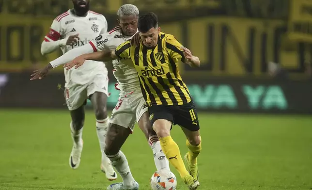 Maximiliano Silvera of Uruguay's Penarol , front, and Wesley Franca of Brazil's Flamengo battle for the ball during a Copa Libertadores quarter final second leg soccer match at Campeon del Siglo Stadium in Montevideo, Uruguay, Thursday, Sept. 26, 2024. (AP Photo/Matilde Campodonico)