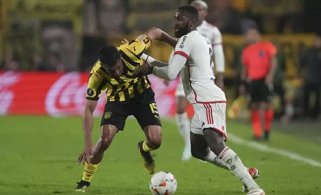 Gerson of Brazil's Flamengo, right, and Maximiliano Olivera of Uruguay's Penarol battle for the ball during a Copa Libertadores quarter final second leg soccer match at Campeon del Siglo Stadium in Montevideo, Uruguay, Thursday, Sept. 26, 2024. (AP Photo/Matilde Campodonico)