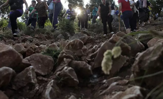 FILE - Pilgrims walk on a rocky terrain to say their prayers on the Hill Of Appearance in Medjugorje, 100 kilometers south of Sarajevo, June 25, 2012. (AP Photo/Amel Emric, File)