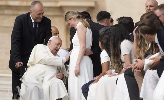 Pope Francis touches the belly of a newly married woman during his weekly general audience in St. Peter's Square, at the Vatican, Wednesday, Sept. 25, 2024. (AP Photo/Gregorio Borgia)