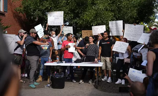 Resident Jaun Carlos Jimenez, center left, listens as Jeraldine Mazo, center right, speaks during a rally staged by the East Colfax Community Collective to address chronic problems in the apartment buildings occupied by people displaced from their home countries in central and South America Tuesday, Sept. 3, 2024, in Aurora, Colo. (AP Photo/David Zalubowski)