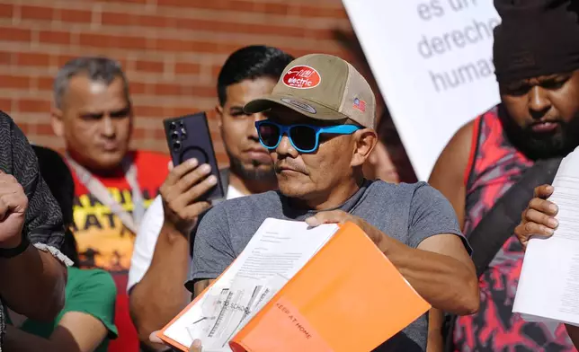 Resident Moises Didenot shows his receipts that he paid rent for his basement apartment during a rally staged by the East Colfax Community Collective to address chronic problems in the buildings occupied by people displaced from their home countries in central and South America Tuesday, Sept. 3, 2024, in Aurora, Colo. (AP Photo/David Zalubowski)