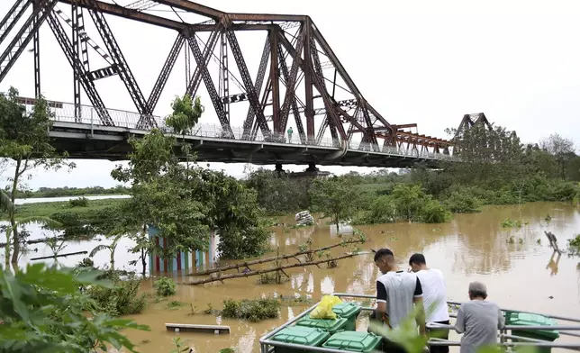 People watch the flooded Red river next to iconic Long Bien bridge, following Typhoon Yagi in Hanoi, Vietnam on Tuesday, Sept. 10, 2024. (AP Photo/Huy Han)