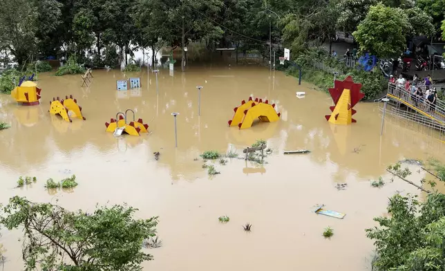 People look on a submerged dragon structure in a playground, following Typhoon Yagi in Hanoi, Vietnam on Tuesday, Sept. 10, 2024. (AP Photo/Huy Han)