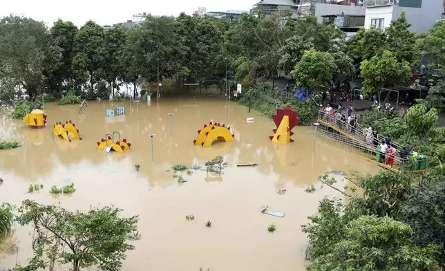 People watch a submerged dragon structure in a playground, following Typhoon Yagi in Hanoi, Vietnam on Tuesday, Sept. 10, 2024. (AP Photo/Huy Han)