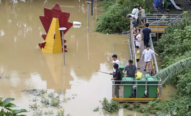 People fish next to a submerged playground due to flood , following Typhoon Yagi in Hanoi, Vietnam on Tuesday, Sept. 10, 2024. (AP Photo/Huy Han)