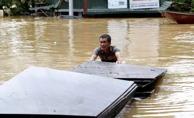 A man pushes a stack of plyboards in flood following Typhoon Yagi in Hanoi, Vietnam on Tuesday, Sept. 10, 2024. (AP Photo/Huy Han)