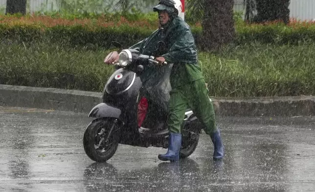 A man pushes a motorcycle in the rain caused by typhoon Yagi in Hanoi, Vietnam Saturday, Sep. 7, 2024. (AP Photo/Hau Dinh)