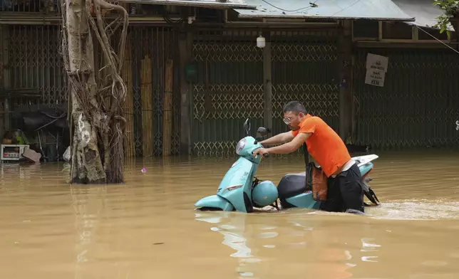 A man pushes his motorcycle in a flooded street in the aftermath of Typhoon Yagi, in Hanoi, Vietnam on Thursday, Sep. 12, 2024. (AP Photo/Hau Dinh)