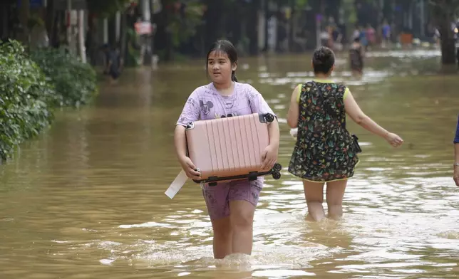 People carrying belongings wade in flooded street in the aftermath of Typhoon Yagi, in Hanoi, Vietnam on Thursday, Sept. 12, 2024. (AP Photo/Hau Dinh)