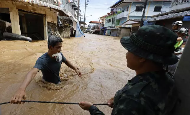 People wade through floodwaters in Chiang Rai Province, Thailand, Friday, Sept. 13, 2024. (AP Photo/Sarot Meksophawannakul)