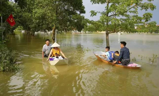 People sit on a boat to get to their flooded homes in the aftermath of Typhoon Yagi in An Lac village, Hanoi, Vietnam Friday, Sept. 13, 2024. (AP Photo/Hau Dinh)