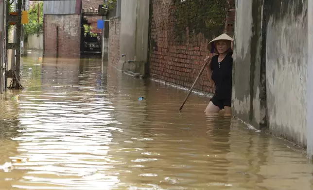 A woman wades in flood in the aftermath of Typhoon Yagi in An Lac village, Hanoi, Vietnam Friday, Sept. 13, 2024. (AP Photo/Hau Dinh)