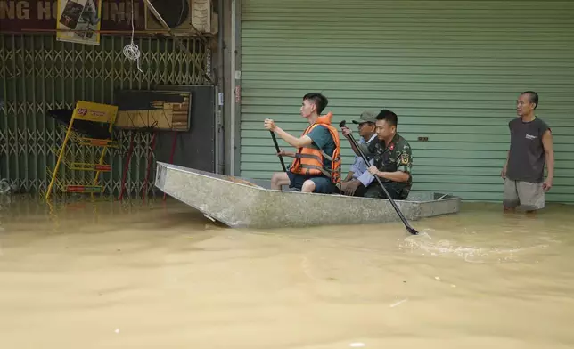 Rescue officers carry people on boat in a flooded street in the aftermath of Typhoon Yagi, in Hanoi, Vietnam on Thursday, Sept. 12, 2024. (AP Photo/Hau Dinh)