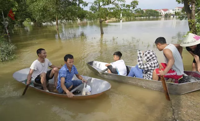 People sit on a boat to get to their flooded homes in the aftermath of Typhoon Yagi in An Lac village, Hanoi, Vietnam Friday, Sept. 13, 2024. (AP Photo/Hau Dinh)